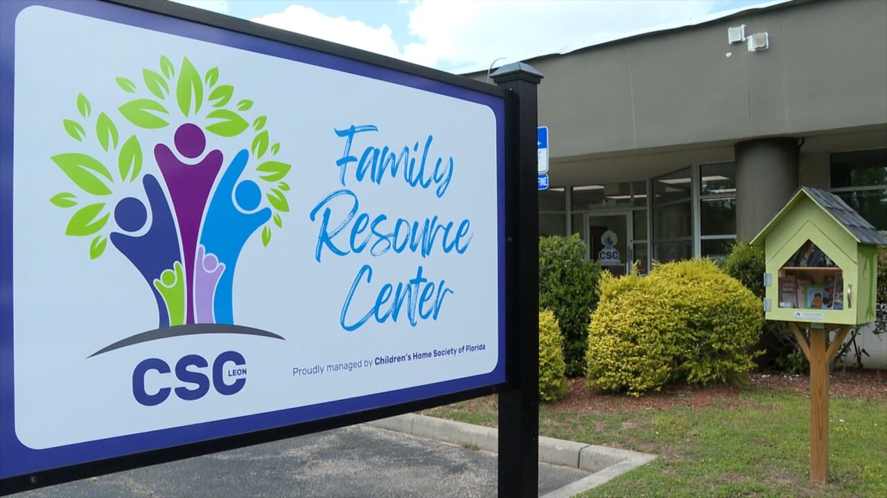 Sign outside a building reading “Family Resource Center” with the CSC logo, set near landscaping. A small outdoor “little free library” box stands nearby in front of the facility.
