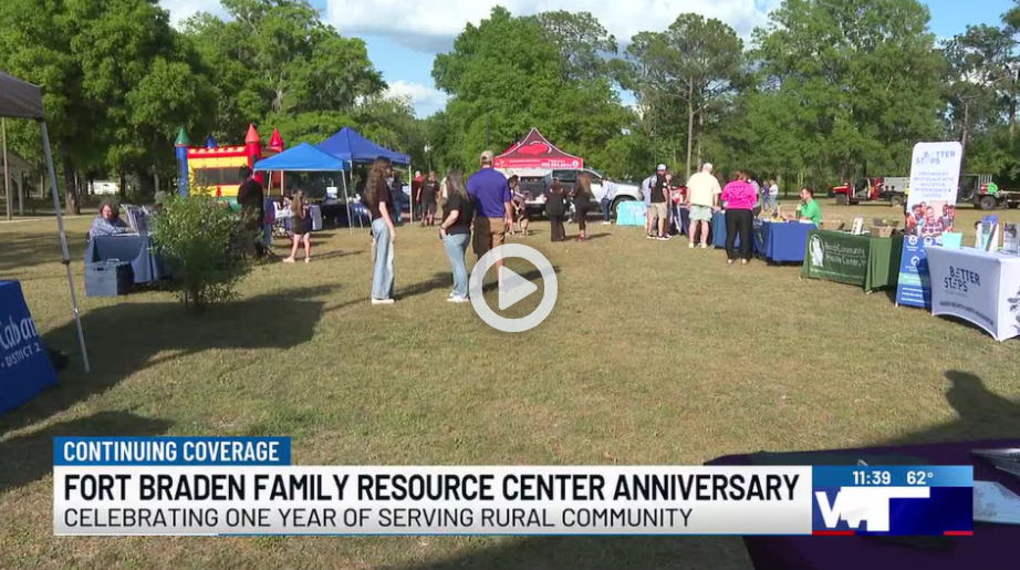 Screenshot from a news video showing an outdoor community event with tents, tables, and families gathered on a grassy field. On-screen text reads “Fort Braden Family Resource Center Anniversary” and “Celebrating one year of serving rural community,” with a WCTV news logo and timestamp visible.